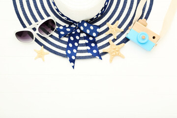 Poster - Summer straw hat with starfishes, sunglasses and decorative camera on white wooden table