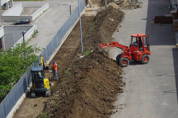 A small red bulldozer and a small yellow excavator during construction work.