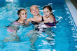 © olenap - Mother with two daughters having fun in indoor swimming-pool. Girl is resting at the water park. Swimming school for small children. Concept friendly family sport summer vacation. Selective focus