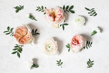 Floral Composition With Pink English Roses, Ranunculus And Green Leaves On White Concrete Table Background. Flower Pattern. Flat Lay, Top View. Wedding Or Birthday Styled Stock Photo.