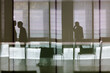 © Bill Gallery - silhouettes of businessmen in building lobby as seen through glass wall at workplace