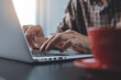 © tippapatt - casual business man hand typing on laptop computer while online working at home