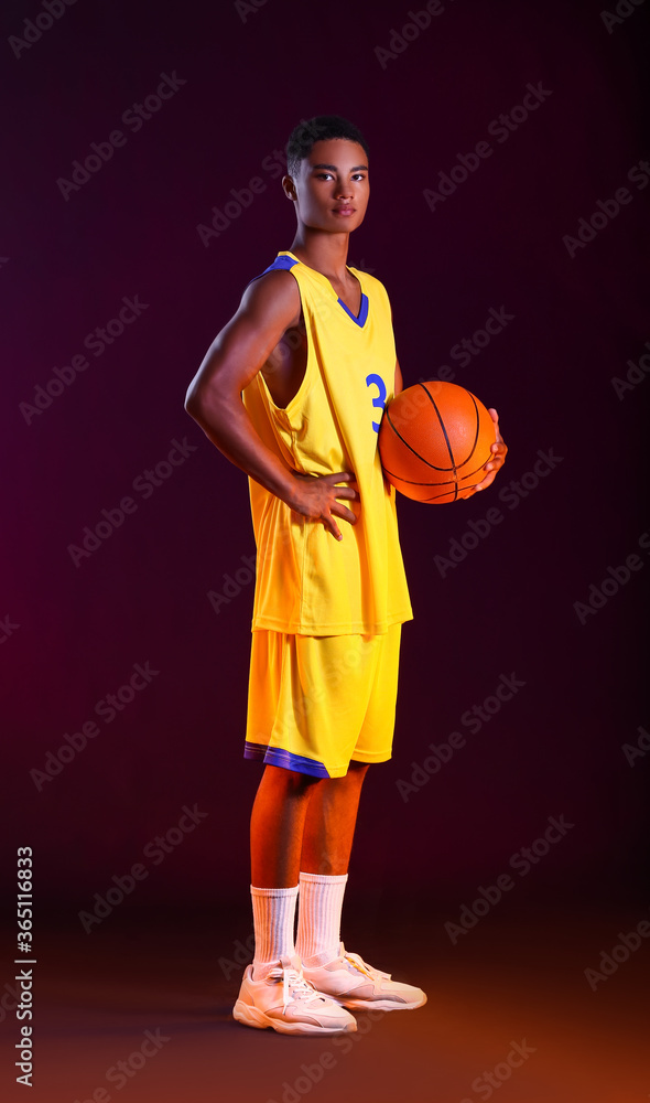 Young African-American basketball player on dark background