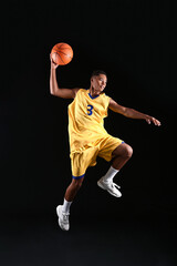 Young jumping African-American basketball player on dark background