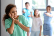 © Pixel-Shot - People bullying African-American woman at the university. Stop racism