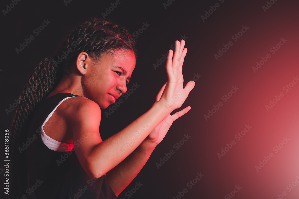 Scared African-American girl on dark background. Stop racism