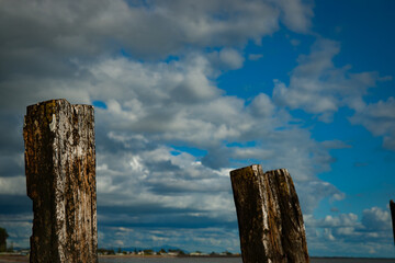 Sticker - Two Old pier posts below cloudy sky.