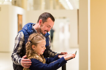 concentrated father and daughter consulting guide during visit to museum