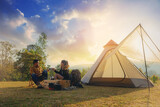 Fototapeta  - Young couples have good time morning on camping trip with sunrise background. Couples enjoy camping with morning coffee.	
