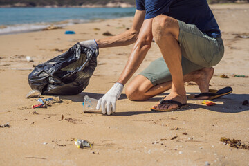 Man in gloves pick up plastic bags that pollute sea. Problem of spilled rubbish trash garbage on the beach sand caused by man-made pollution and environmental, campaign to clean volunteer in concept