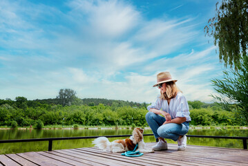 Wall Mural - Woman and her puppy relaxing together at the lake