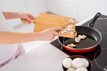 Cropped top above high angle photo of gourmet tasty supper menu preparation woman add mushrooms frying pan chopping board in house indoors