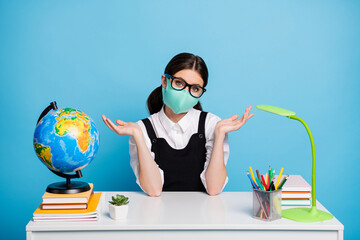 Poster - Photo of frustrated girl college student sit table shrug shoulders dont know when quarantine end wear white blouse black overall uniform medical mask isolated over blue color background