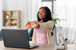 © Syda Productions - remote job, e-learning and people concept - happy smiling young african american woman with laptop computer stretching at home office