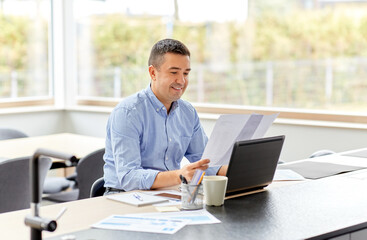 remote job, business and people concept - happy smiling middle-aged man with laptop computer and papers working at home office