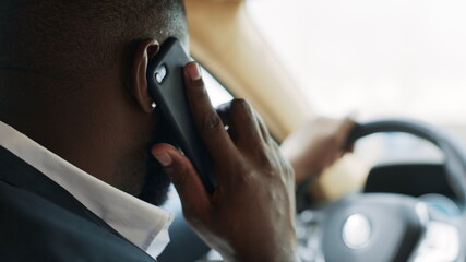 Back view of african man talking phone at car. Man sitting behind steering wheel