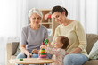 © Syda Productions - family, generation and female concept - happy smiling mother, baby daughter and grandmother playing with toy pyramid at home
