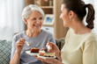 © Syda Productions - family, generation and people concept - happy smiling senior mother and adult daughter eating cake at home