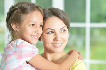 Wall Mural - Portrait of a charming little girl hugging with mom at home