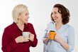 © ladyalex - Two healthy and beautiful middle aged women drinking tea and talking isolated on white background. Woman support woman. Happy menopause concept.