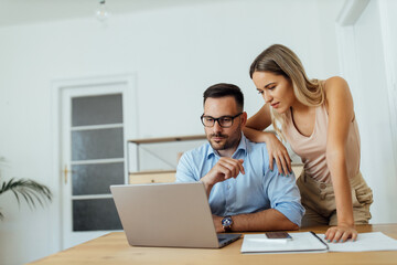 Wall Mural - Beautiful business couple looking at laptop, portrait.