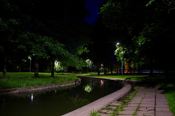 Night city park with a river and beautiful lanterns in summer