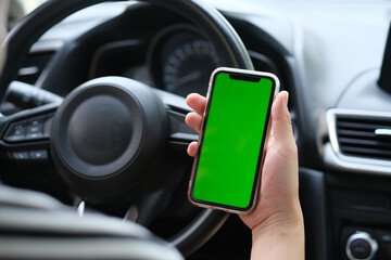 Wall Mural - over shoulder of man holding green screen smart phone in the car. blur background