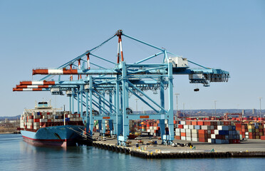 Newark, NJ / USA - View of the container terminal with berthed ship, gantry cranes are loading and discharging cargo from the vessel.