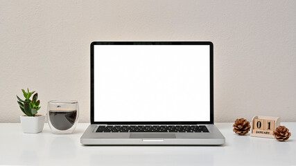 Wall Mural - Modern workspace with blank screen laptop, coffee cup and calendar on white background. Front view. Happy new year day.