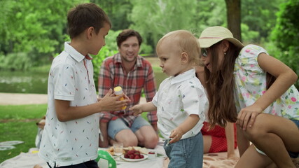 Wall Mural - Happy siblings playing together in forest. Smiling family having picnic outdoors