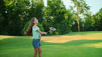 Wall Mural - Girl holding badminton racket in hand. Smiling teen playing badminton in park