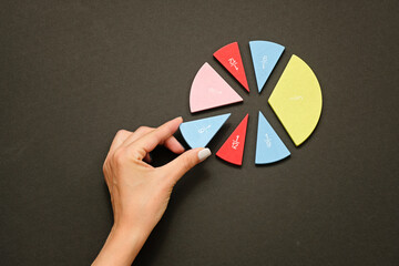 colorful fraction circles arranged into a circle graph and hand, black background.