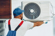 © fotofabrika - Repairman in uniform installing the outside unit of air conditioner
