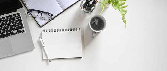 Top view white workspace is surrounding by a coffee cup and various equipment.