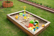 children's sandbox with toys on green grass