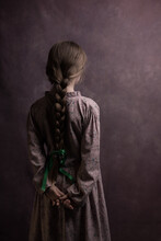 Classic Studio Portrait In Painterly Style Of Girl With Braid With Ribbon Seen From Behind Wearing A Purple Vintage Dress