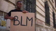 Afro American Man Holding A Makeshift Poster With The Inscription BLM. Black Lives Matter, Outdoor Portrait. Protests In The USA