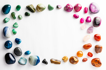 Colorful semi-precious stones arranged neatly with a circular empty space among them on a white background