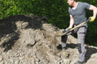 © oleksandr - A man working with a shovel near a heap of soil.