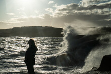 Beautiful Silhouette Of A Girl Posing In Front Of Big Waves Crashing In Over The Rocky Shore