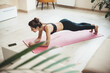© Strelciuc - Caucasian brunette woman planking at home during the lockdown wearing sportswear and using a laptop with phone