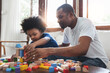 © eggeeggjiew - African Dad and son sitting playing colourful wood blocks toy together