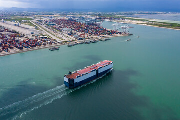 car carrier sailing on the green sea and international shipping container port  background