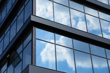 facade of a modern building on a bright Sunny day, blue sky and clouds reflecting in a glass, beautiful exterior of the new building