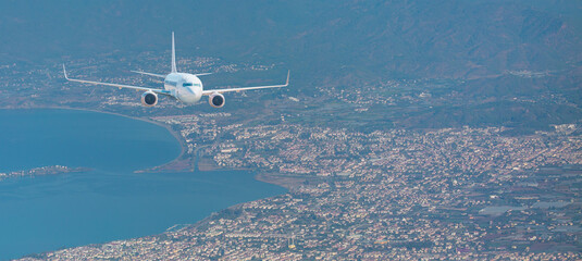 Airplane taking off from the airport - White commercial airplane flying over city and lake