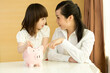 © JodieWang - Parents teaching daughter to save money at home