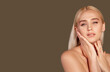 © golubovy - Beauty portrait. Aesthetic cosmetology. Blonde woman with bare shoulders touching face isolated on brown empty space.