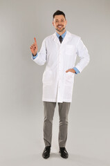 Wall Mural - Happy man in lab coat on light grey background