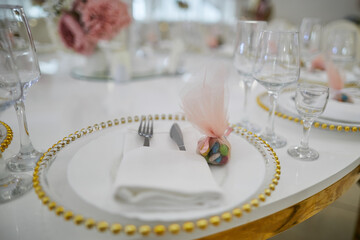 white plate with a golden edge, glasses and cutlery on a table in a restaurant