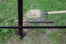 White Pebble On A Shovel, Strengthening With Gravel Of Columns Of Supports Of The Base Of A New Metal Fence